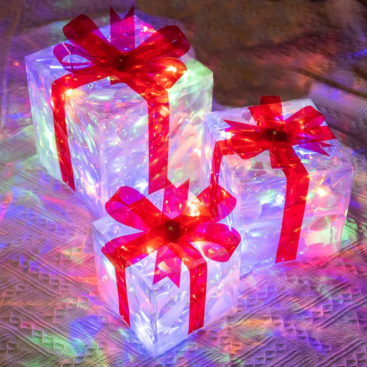 Multicolor lighted Christmas gift boxes with red bows and LED lights glowing indoors on a festive background.