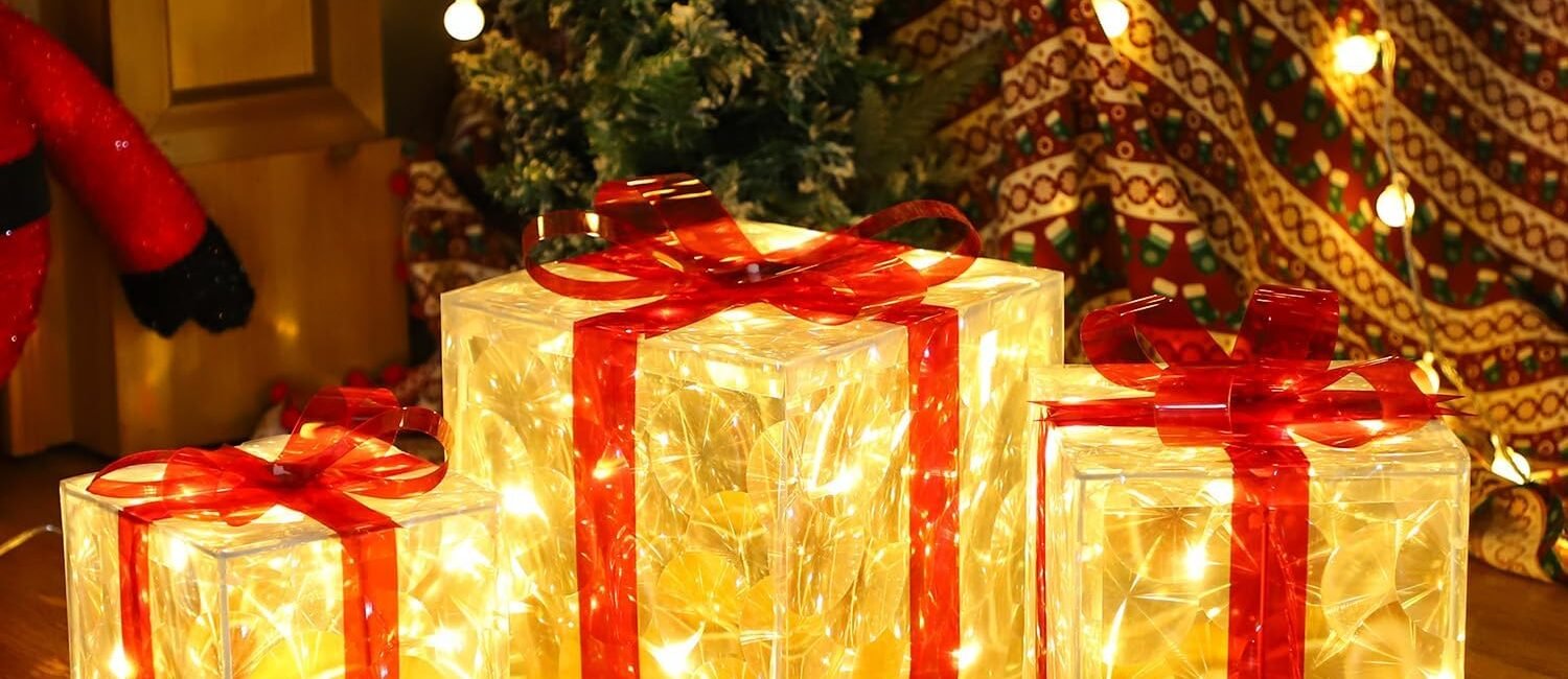 Set of three lighted Christmas gift boxes with red bows and warm white LED glow under a holiday tree.