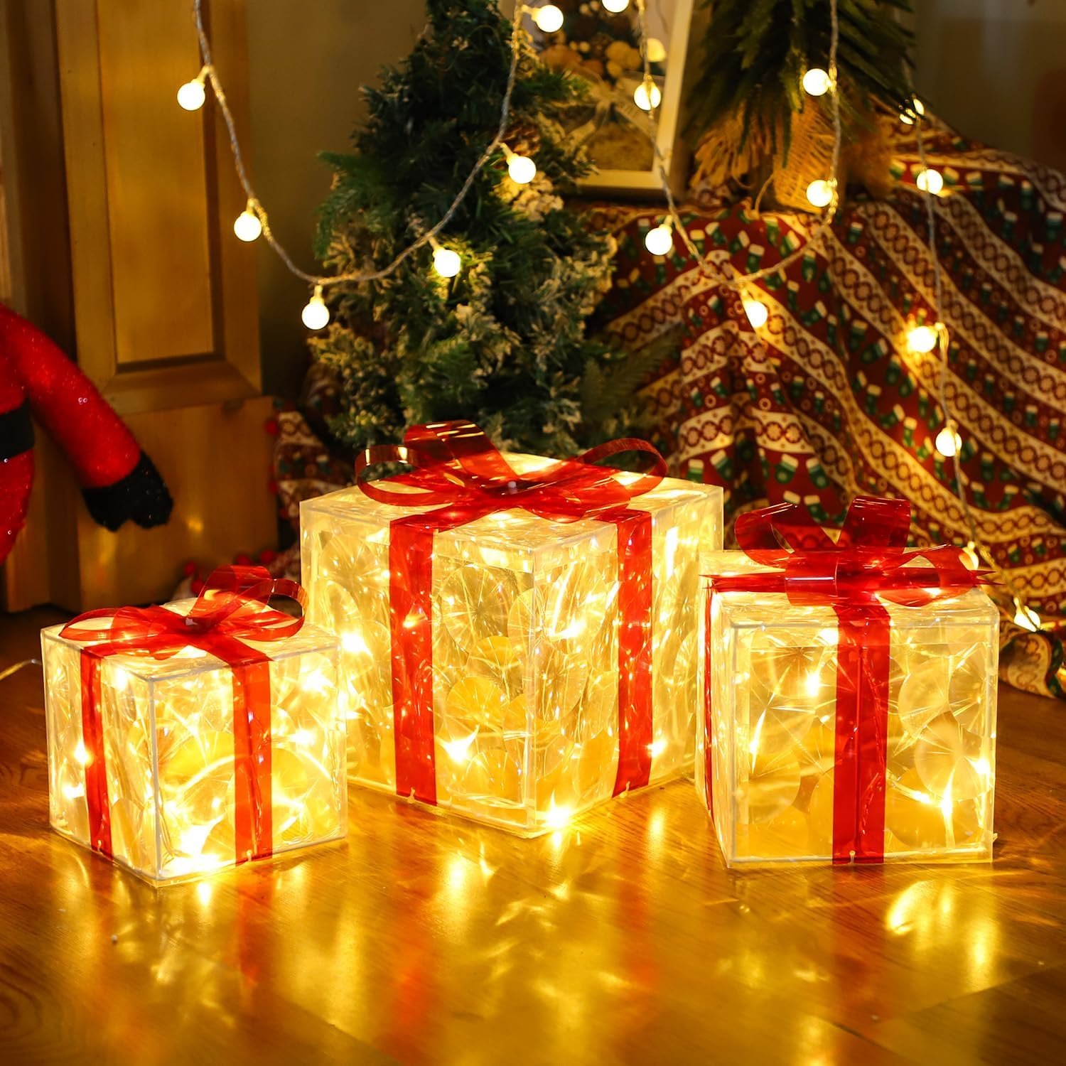 Set of three lighted Christmas gift boxes with red bows and warm white LED glow under a holiday tree.