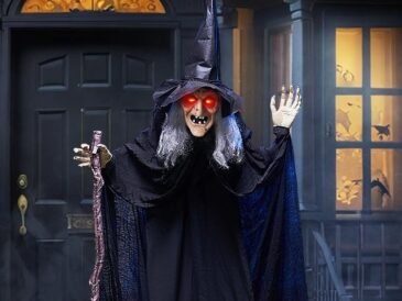 Life-size Halloween witch prop with glowing eyes and cane for outdoor yard decoration.