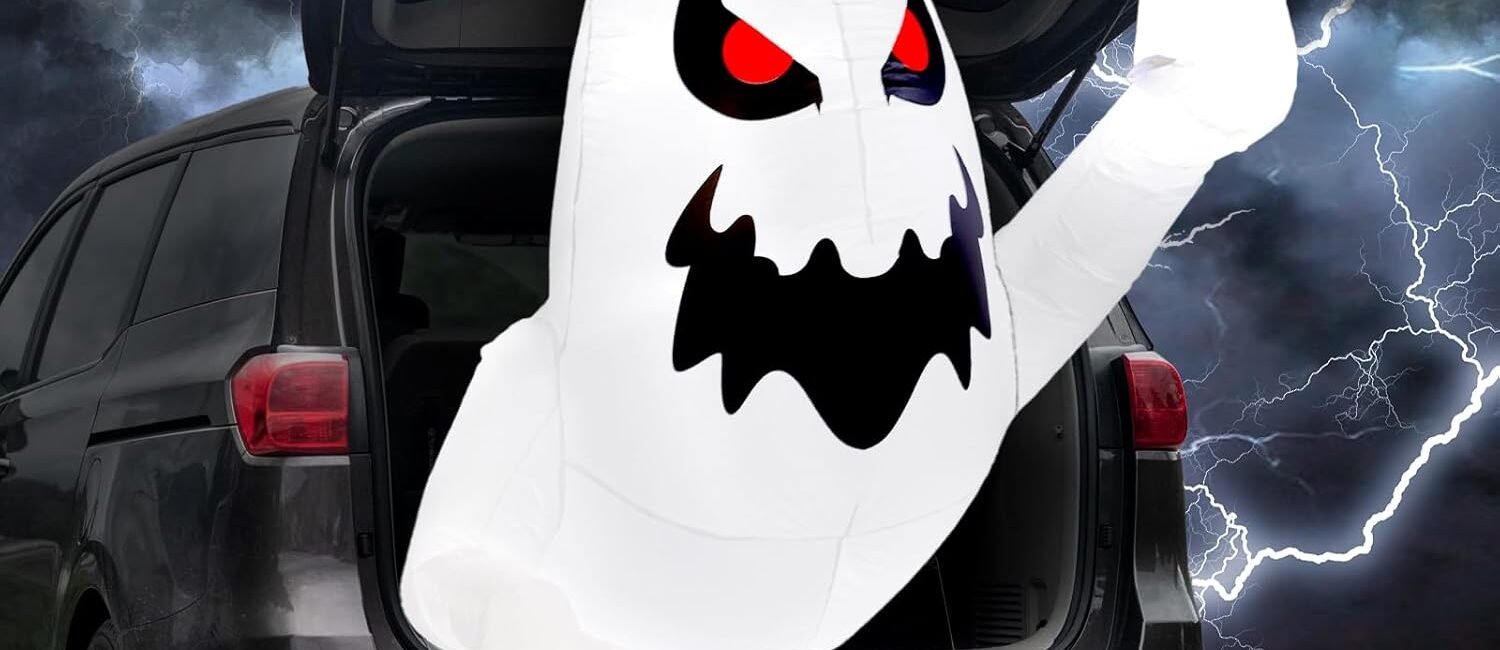 White inflatable Halloween ghost glowing with LED lights, emerging from car trunk with red eyes.