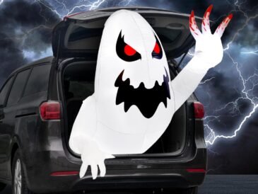White inflatable Halloween ghost glowing with LED lights, emerging from car trunk with red eyes.