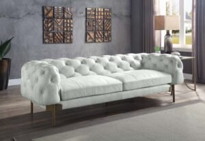 Vintage white Chesterfield sofa with tufted leather and metal legs.