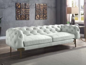 Vintage white Chesterfield sofa with tufted leather and metal legs.