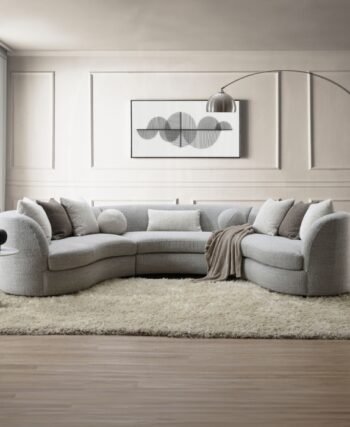 Curved gray boucle sectional sofa with feather-filled pillows in a modern neutral living room setting.