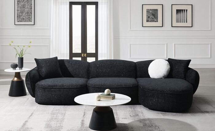 Curved black chenille sectional sofa with accent pillows in a modern living-room setting.