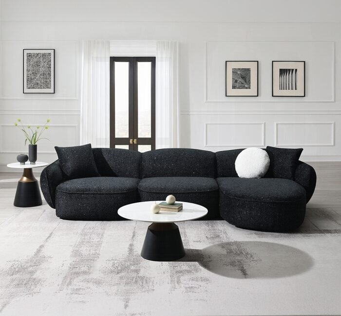 Curved black chenille sectional sofa with accent pillows in a modern living-room setting.