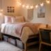 Styled dorm room with made bed, string lights, desk with lamp, and under-bed storage