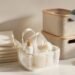Flat lay of dorm essentials including bedding, shower caddy, storage bins, and a desk lamp