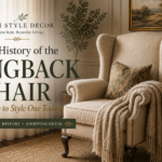 Cream wingback chair with nailhead trim styled beside a dark wood table in an elegant living room, featured in a guide to wingback chair history and styling.